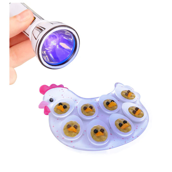 A close-up showing a UV flashlight beam being used to cure the resin on a completed miniature Chick Deviled Eggs platter shaped like a white hen.