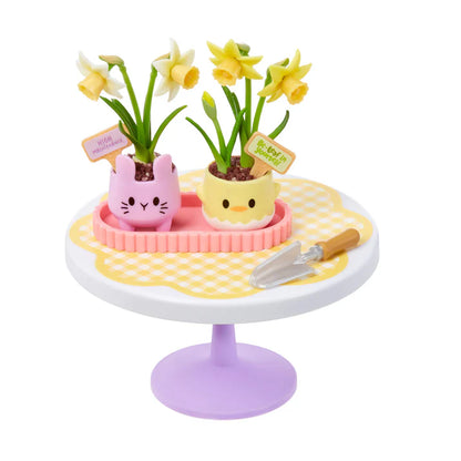 A completed set of the Ultra Rare Miniverse Daffodils planted in cute pastel pink bunny and yellow chick ceramic pots, sitting on a floral display table.