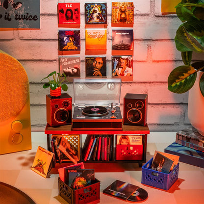 A hot pink mystery blind pack ball for MGA's Miniverse Real Music Vinyl surrounded by mini playable vinyl records, sleeves, and crates.