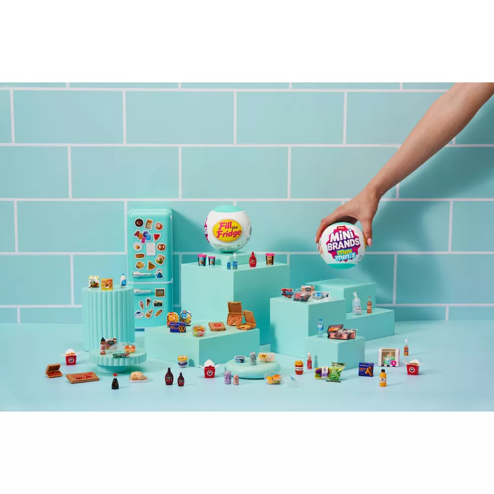 Hand holding a toy packaging with miniature models on a blue tiled background