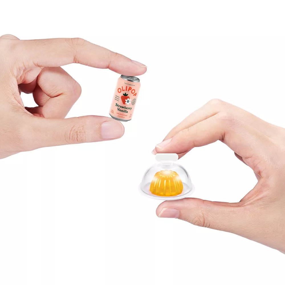 Small jelly-like dessert in a clear container held by hands with a can of strawberry vanilla drink in the background.