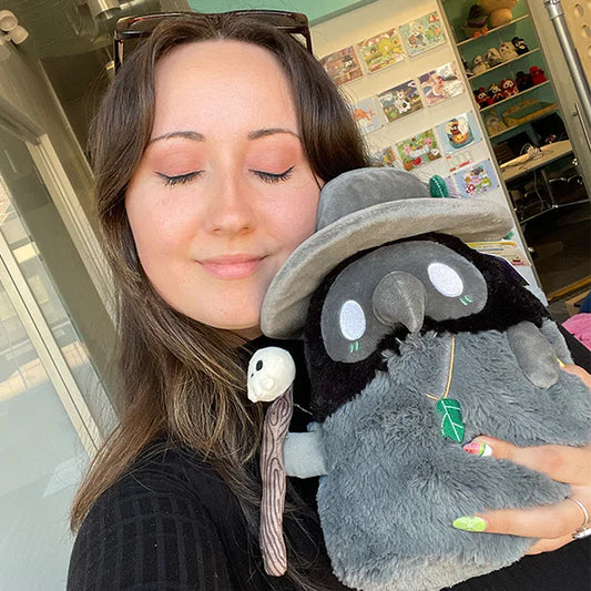 Woman holding Mini Squishable Druid Plague Doctor plush in forest green robes with leafy details