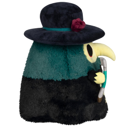 side view of Mini Squishable Graveyard Plague Doctor plush with black cloak, rose hat, and shovel accessory