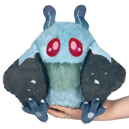 Mini Squishable Haunted Mothman plush featuring light blue fur, glowing red eyes, and dark tattered wings.