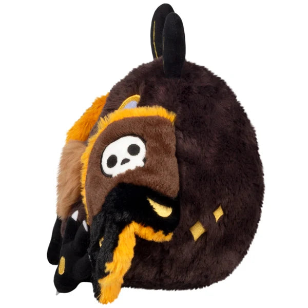 Mini Squishable Hawkmothman plush featuring dark brown fur, yellow eyes, and dark wings with skull patterns.