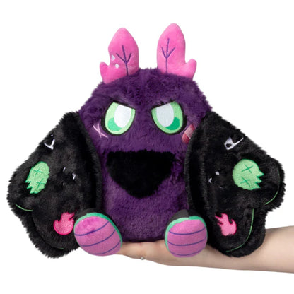 Mini Squishable Neon Punk Mothman plush with deep purple fur, neon pink antennae, bright green eyes, and patch-embellished black wings.