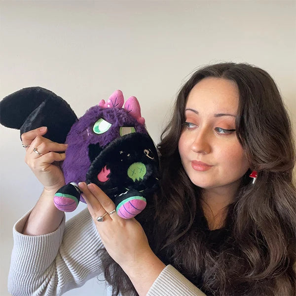 Woman Mini Squishable Neon Punk Mothman plush with deep purple fur, neon pink antennae, bright green eyes, and patch-embellished black wings against a plain background