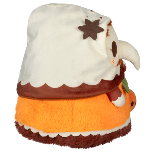 Side view of Mini Squishable Pumpkin Spice Plague Nurse plush with pumpkin accessory