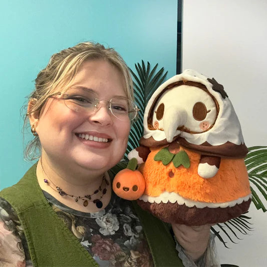 Woman holding Mini Squishable Pumpkin Spice Plague Nurse plush with pumpkin accessory