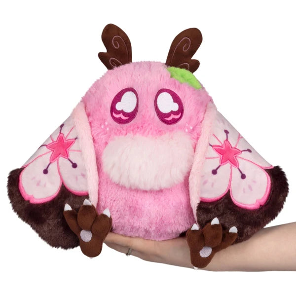 Mini Squishable Sakura Mothman plush with a pink body, fluffy white belly, brown antennae, and pink wings featuring cherry blossom designs.