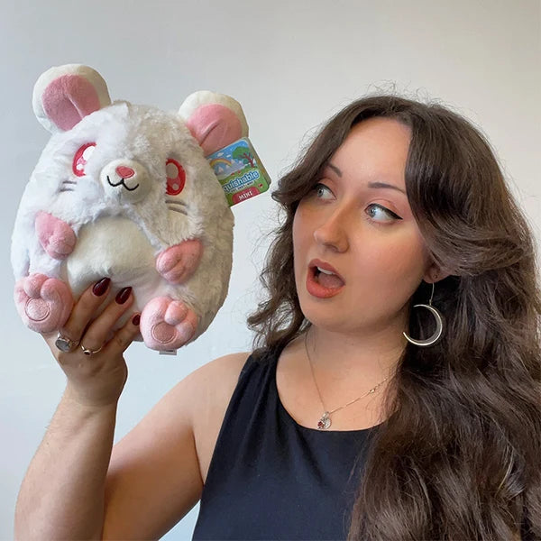 Woman holding a Mini Squishable White Rat plush featuring fluffy white fur, pink ears and paws, red-hued eyes, and a pink tail with a surprised expression