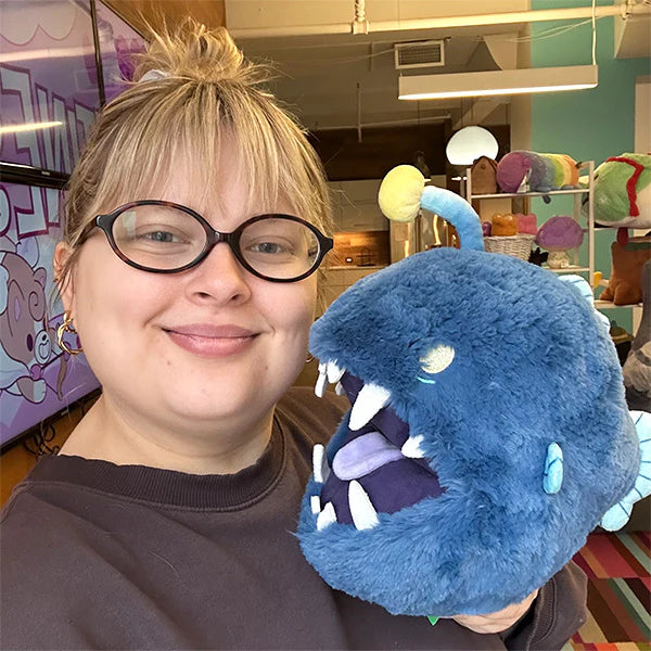 Person holding a blue plush toy in an indoor setting