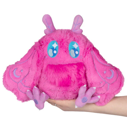 Squishable Mini Pink Baby Mothman plush toy with blue accents held in a hand on a white background
