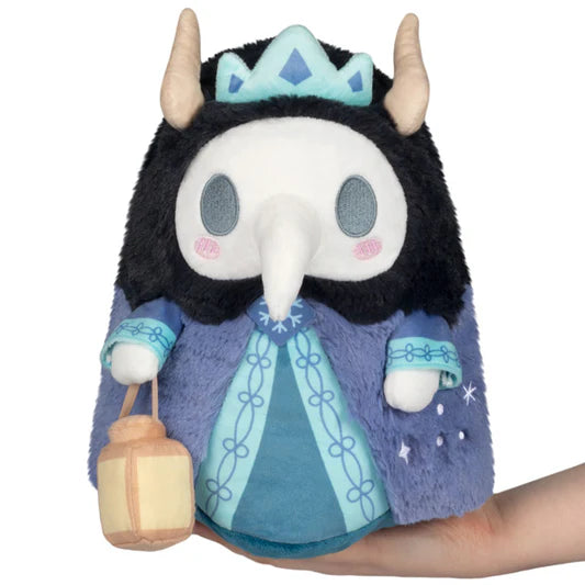 Squishable Mini Solstice Plague Doctor Plush toy with a black hood, blue dress, and crown held by a hand on a white background