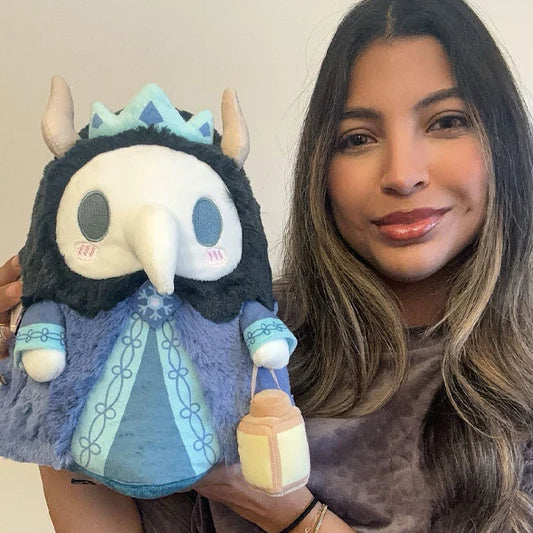 Person holding a plush toy with horns and a blue outfit