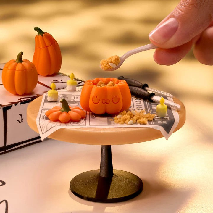 Pumpkin-shaped bowls with a hand holding a spoon over a small table.   Miniverse Make it Mini Halloween Series 3.
