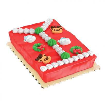 A rectangular red frosted cake decorated with white piped borders, green and white wreaths with red bows, reindeer faces, and white snowflake decorations, shown on a plain white background.