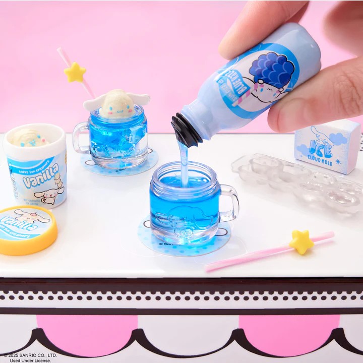 Hand pouring blue liquid from a bottle into small glass cups with ice cubes on a pink background. Miniverse Make It Mini Hello Kitty Series 2.