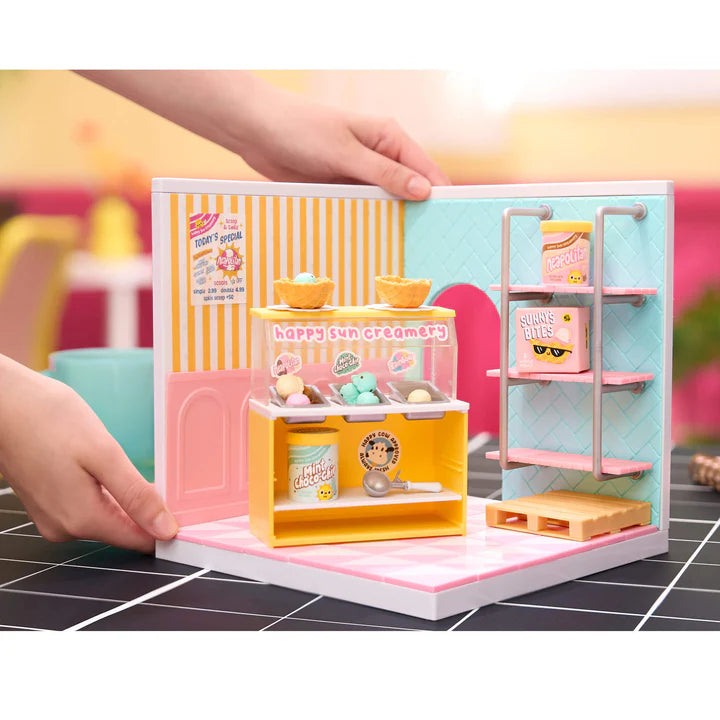 Small toy ice cream shop with a hand interacting with it on a tiled floor. Miniverse Spaces Ice Cream Shop Starter Pack display set Canada
