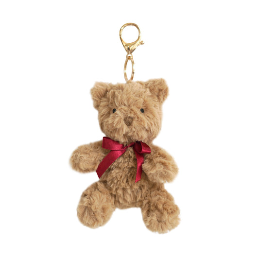 Mon Ami 3-inch Huggie Bear Bag Charm featuring a soft brown plush bear with a red ribbon and a gold-tone metal clasp.