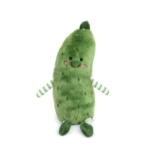 A green pickle-shaped plush toy sitting down, with a smiling embroidered face and pink cheeks. It has green and white striped arms and legs with green feet.