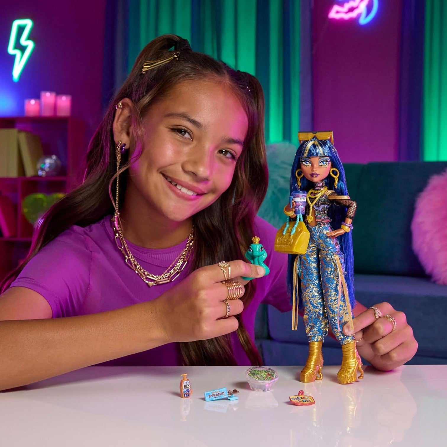 Young girl holding a Monster High Cleo De Nile Core Refresh dollwith a colorful background