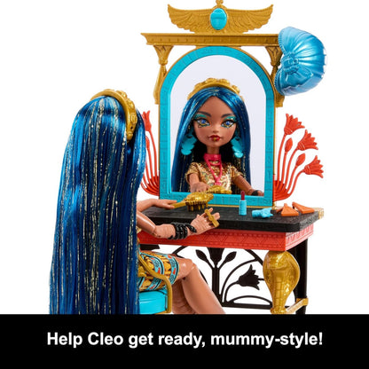 Toy doll with blue hair sitting at an Egyptian-themed vanity mirror and table.