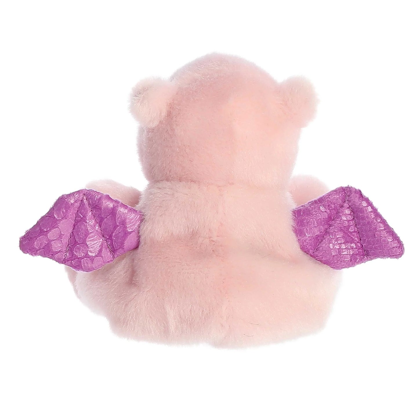 Back of A small, soft pink plush dragon (Palm Pals Aria) sitting down, with shiny, textured purple wings and small black eyes.