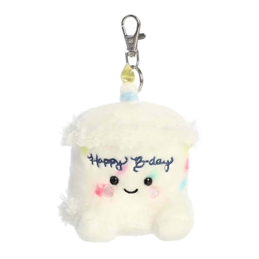 Product view of the Palm Pals Happy B-Day Cake, a 4-inch plush cake slice with confetti and a candle, featuring a plastic keychain clip.
