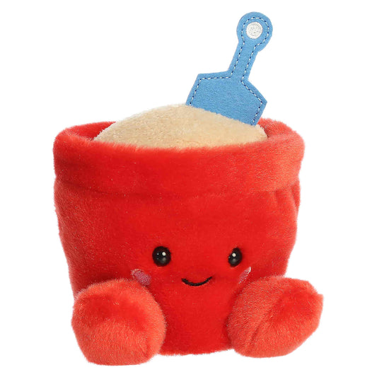 Palm Pals June Sand Bucket, a small red plush shaped like a beach bucket filled with sand and a blue shovel, featuring a sweet smiling face.