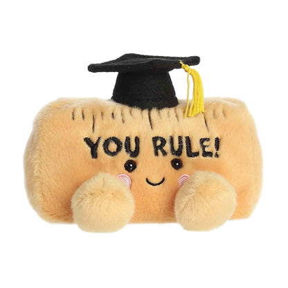 Plush toy resembling a ruler with a graduation cap and 'YOU RULE!' text on a white background