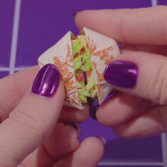 MGA's Miniverse Make It Mini Taco Bell surprise ball and various miniature food ingredients including a Crunchwrap Supreme and sour cream.