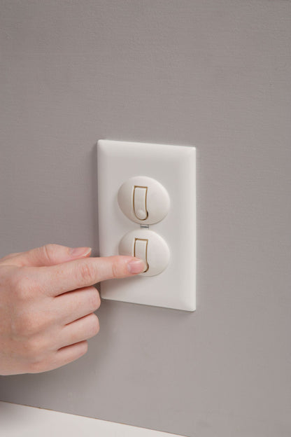Hand pressing a light switch on a gray wall