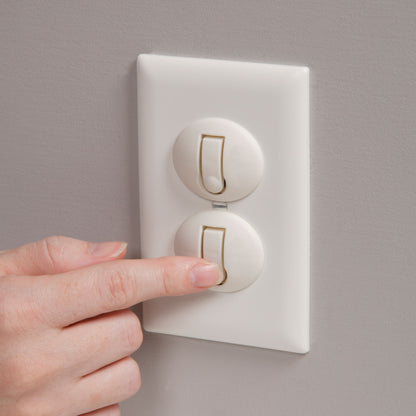 Hand pressing a light switch on a gray wall