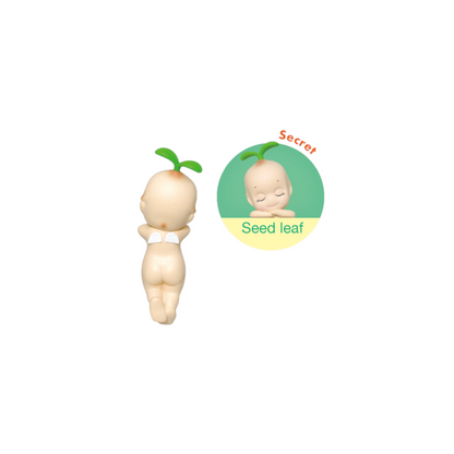 Toy figure resembling a baby with a seed on its head, on a white background