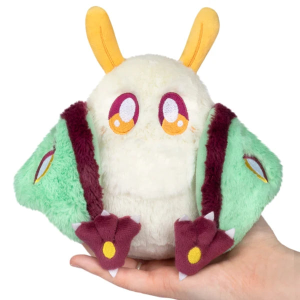 Squishable Alter Egos Series 21 Luna Mothman plush with cream fur, yellow antennae, burgundy feet, and mint green wings.