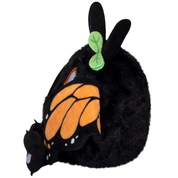 Squishable Alter Egos Series 21 Monarch Mothman plush with black fur, orange glowing eyes, a leaf accent, and monarch butterfly wings.