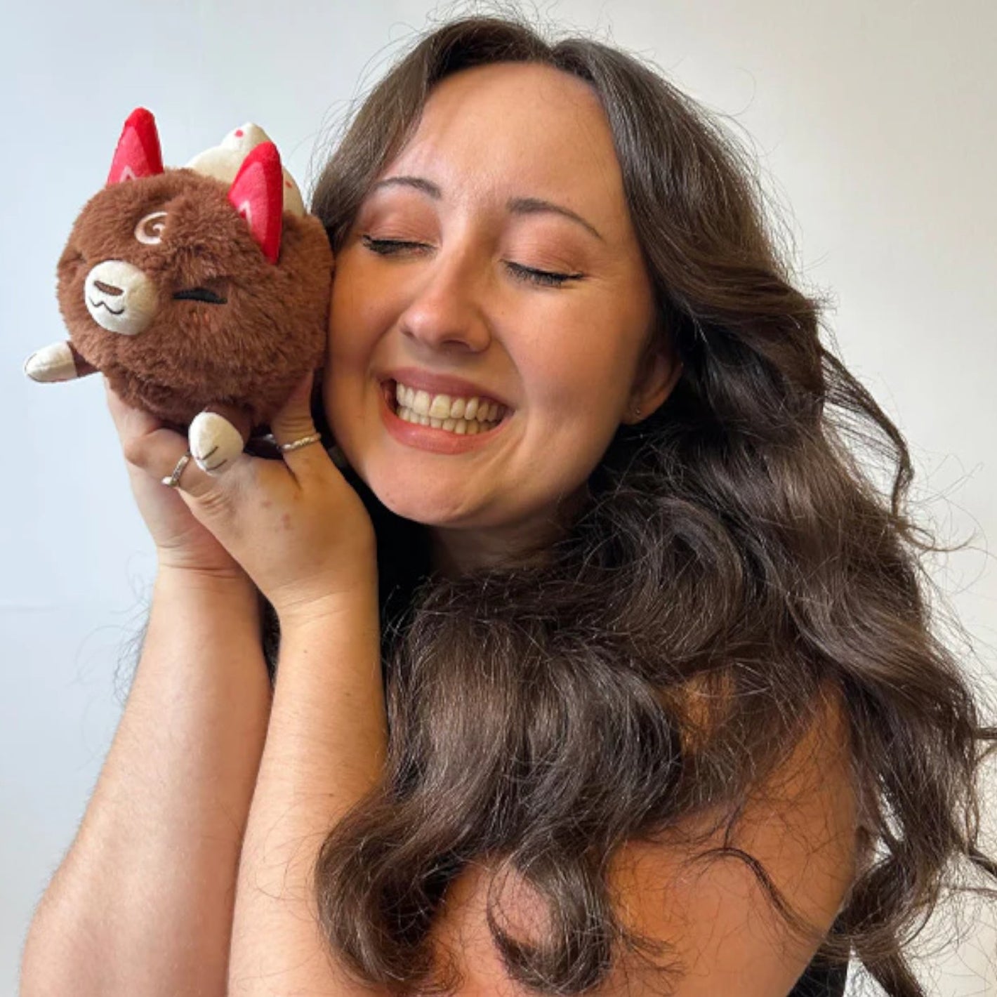 Woman holding Squishable Cocoa Kitsune plush with chocolate-colored fur 