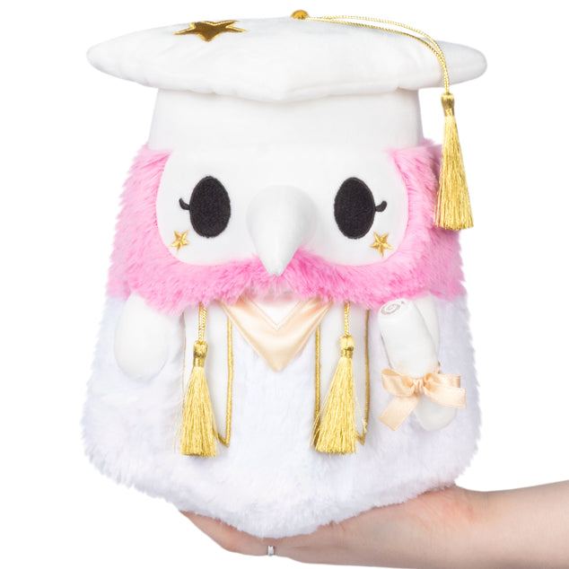 Squishable Mini Graduation Plague Nurse 10-Inch Plush, a white soft toy with a pink collar, gold tassels, and a graduation cap