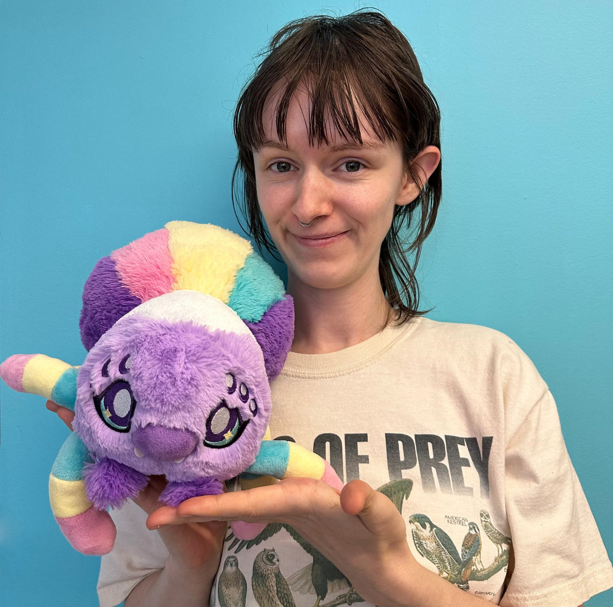 Person holding a colorful plush toy against a blue background