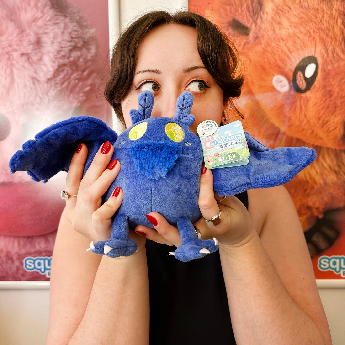 Person holding a blue plush toy with a visible brand label against a colorful background