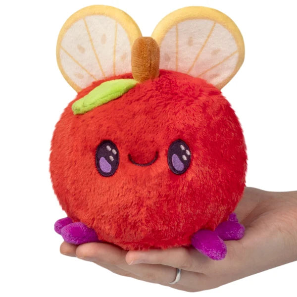 Squishable Snacker Fruit Fly S1E3 limited edition plush shaped like a red apple with citrus slice wings and purple feet.