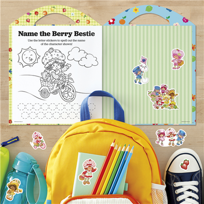 Coloring book with stickers and school supplies on a wooden surface