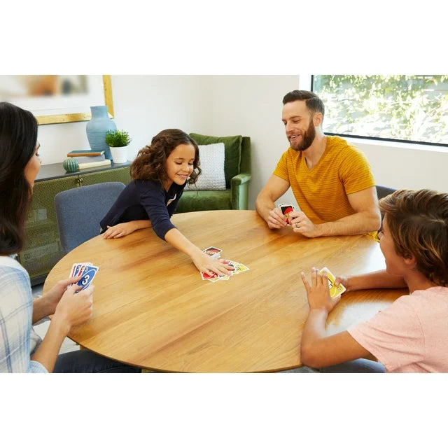 Family playing cards together at a wooden table in a living room.