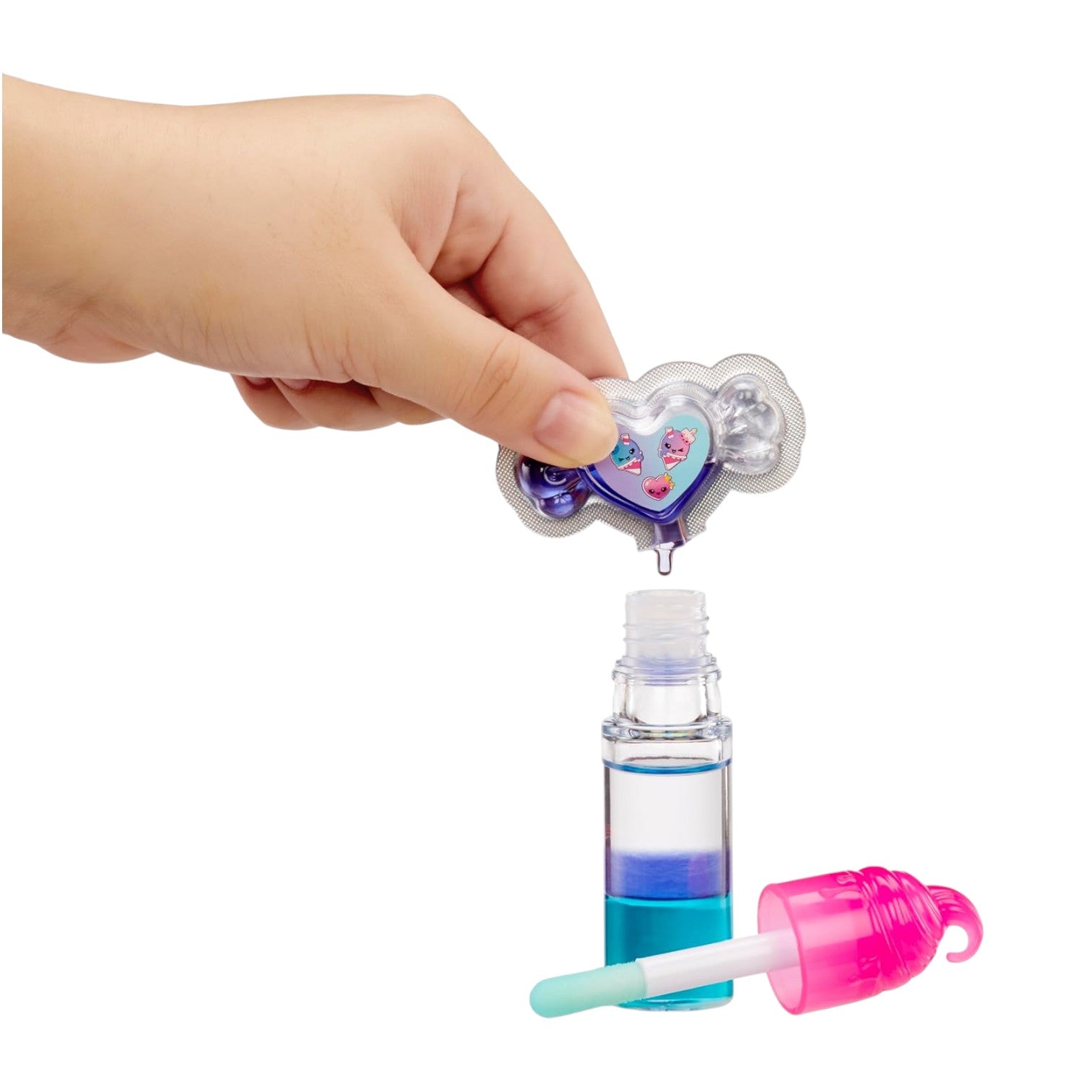 Hand holding a Yummiland Lip Gloss Doll Stephie Snowcone two-tone DIY lip gloss kit with a heart design on a white background