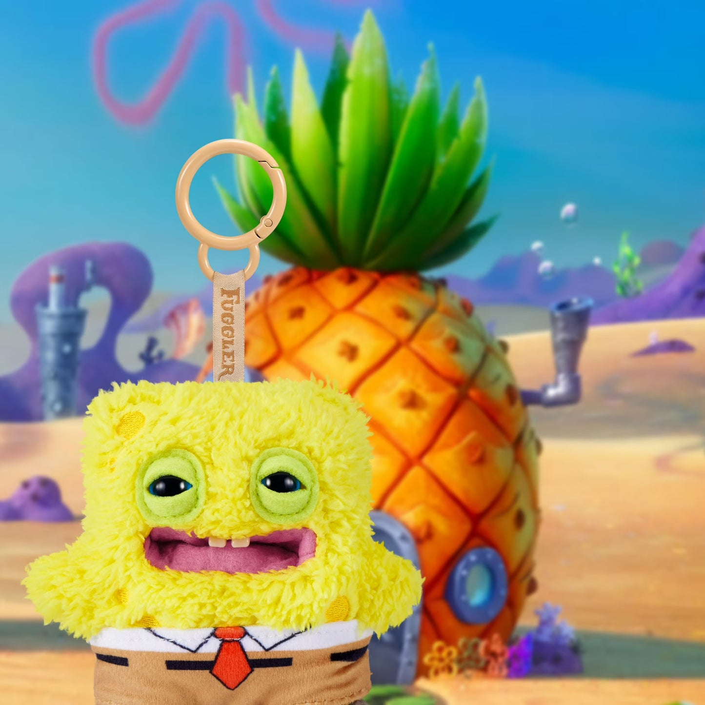 Plush keychain of a cartoon character in front of a pineapple house with a colorful underwater background.